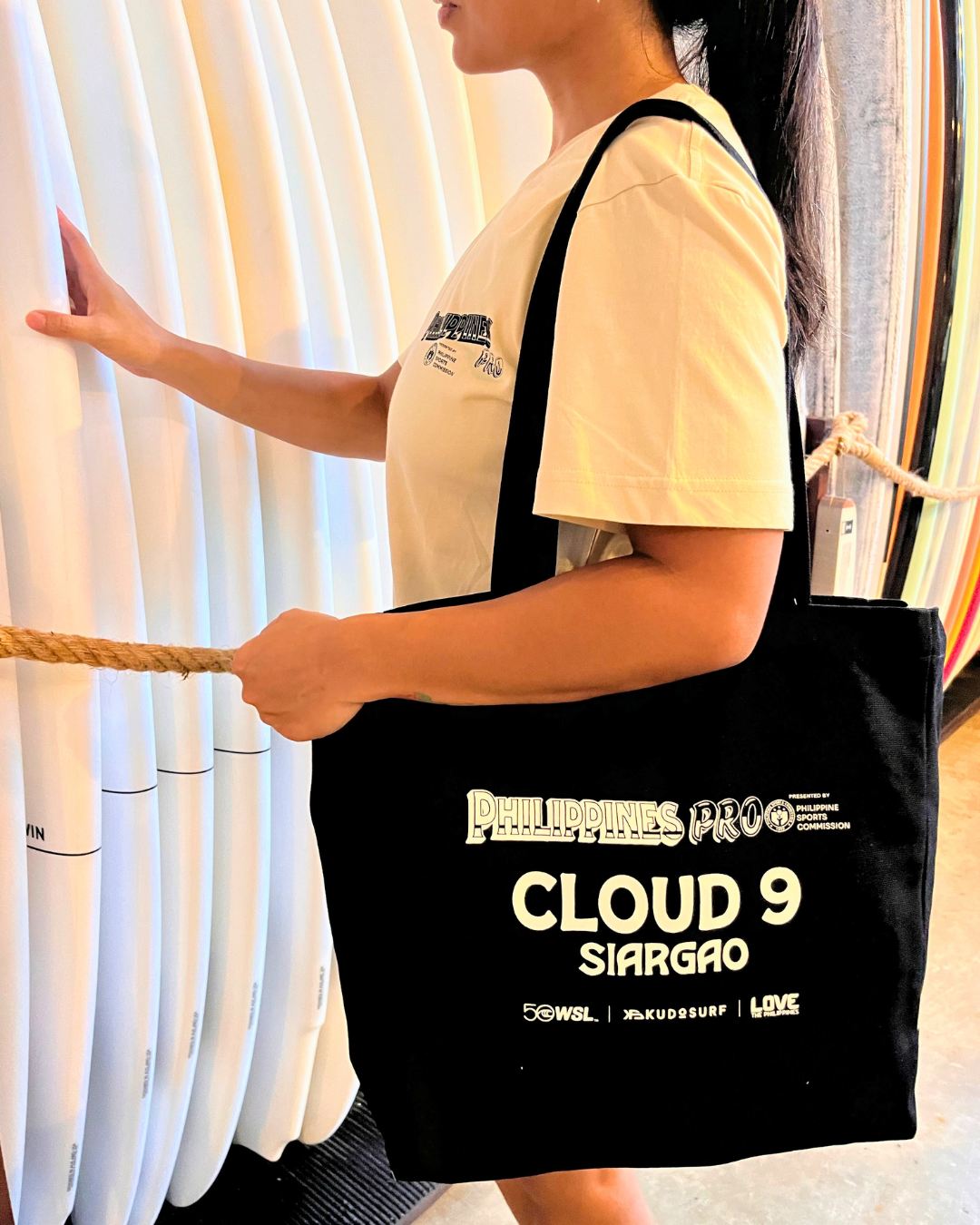 Black Philippines Pro Cloud 9 Siargao tote bag beside surfboards
